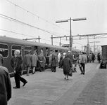 856825 Afbeelding van in- en uitstappende treinreizigers op een onbekend station.